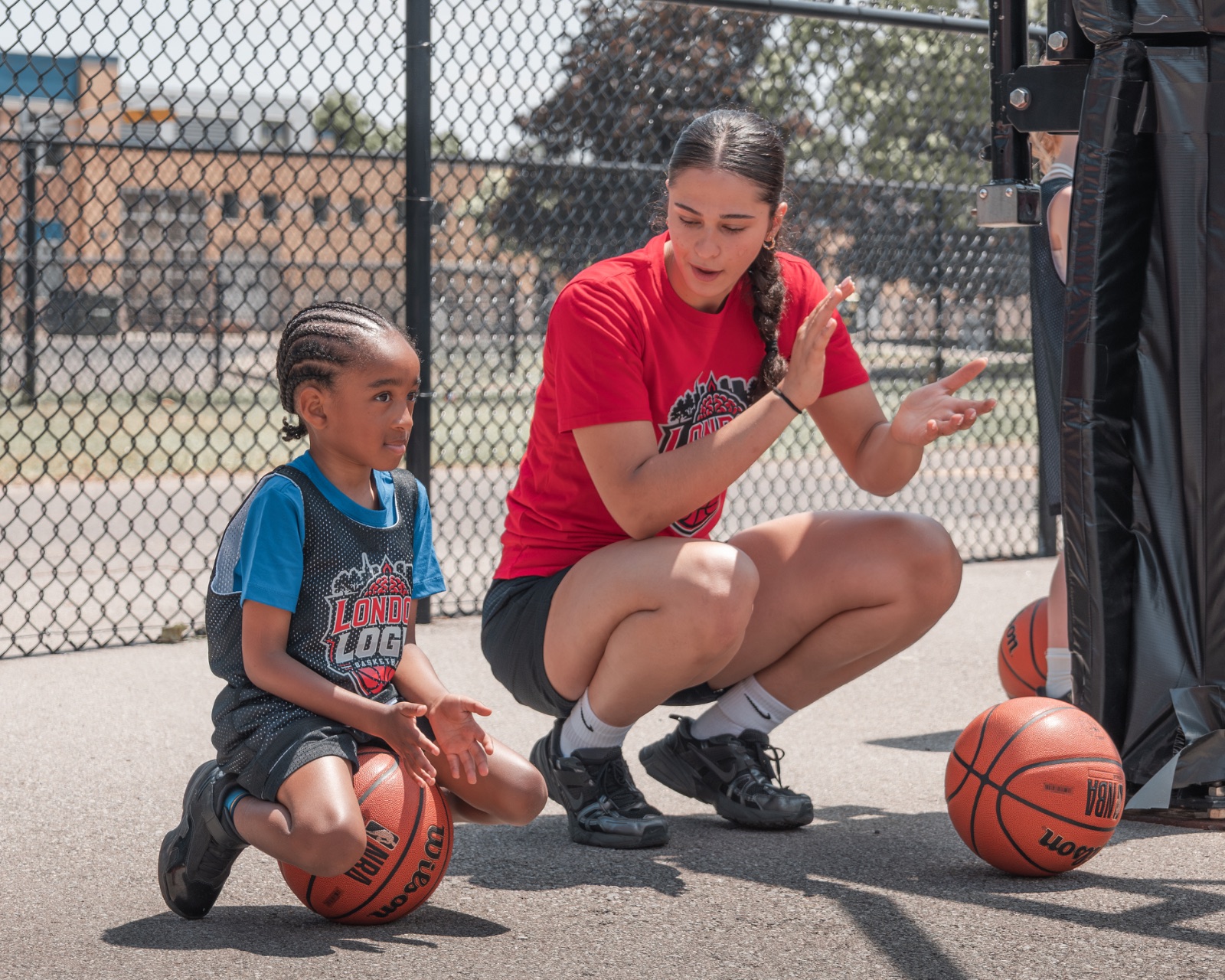 A LOGIC coach breaking down footwork with a young athlete on the court