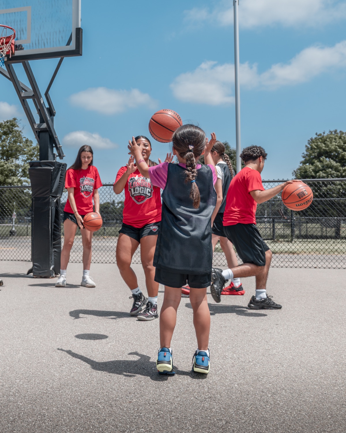 Athletes running a passing and reaction drill under the hoop at camp